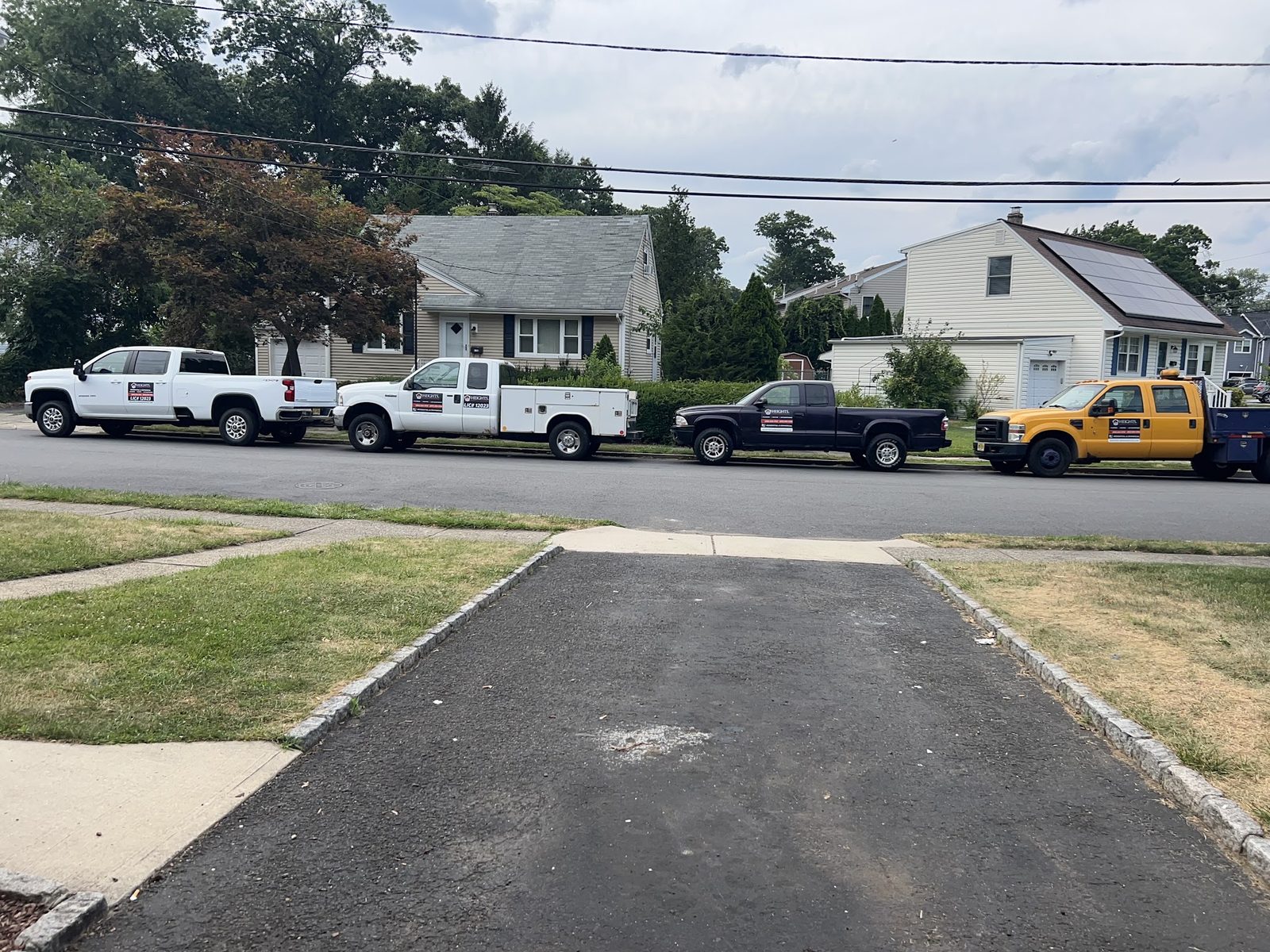 Heights Plumbing, Heating & Cooling service trucks lined up on a residential street in Bergen County, NJ